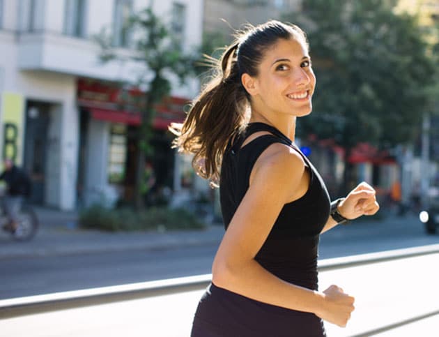 Outdoor shot of happy young woman jogging in city